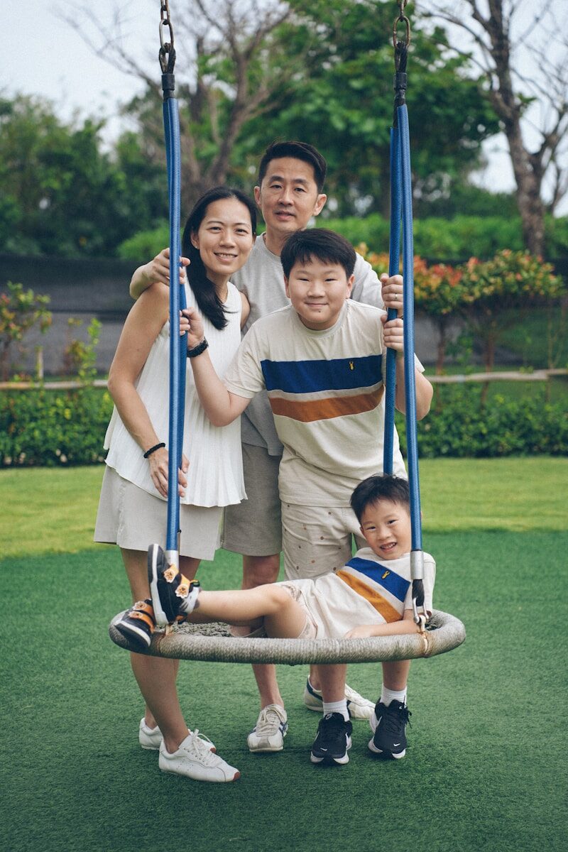 A family posing on a swing set outdoors